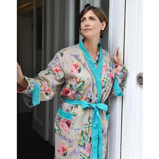 Women's Robe. Floral Blush printed dressing gown is  made from beautiful 100% lightweight breathable cotton. The floral print is like a vintage country garden with pink roses in full bloom, pretty lilac and yellow flowers and green leaves. It has trimmed pale teal cotton on the pockets, cuffs and open front, which is accented with pom-poms. It ties with a long matching belt. It is so chic and very comfortable to wear.